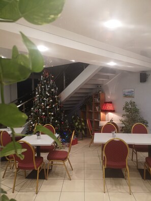 Cozy dining area with a Christmas tree, red chairs, and a bookshelf.