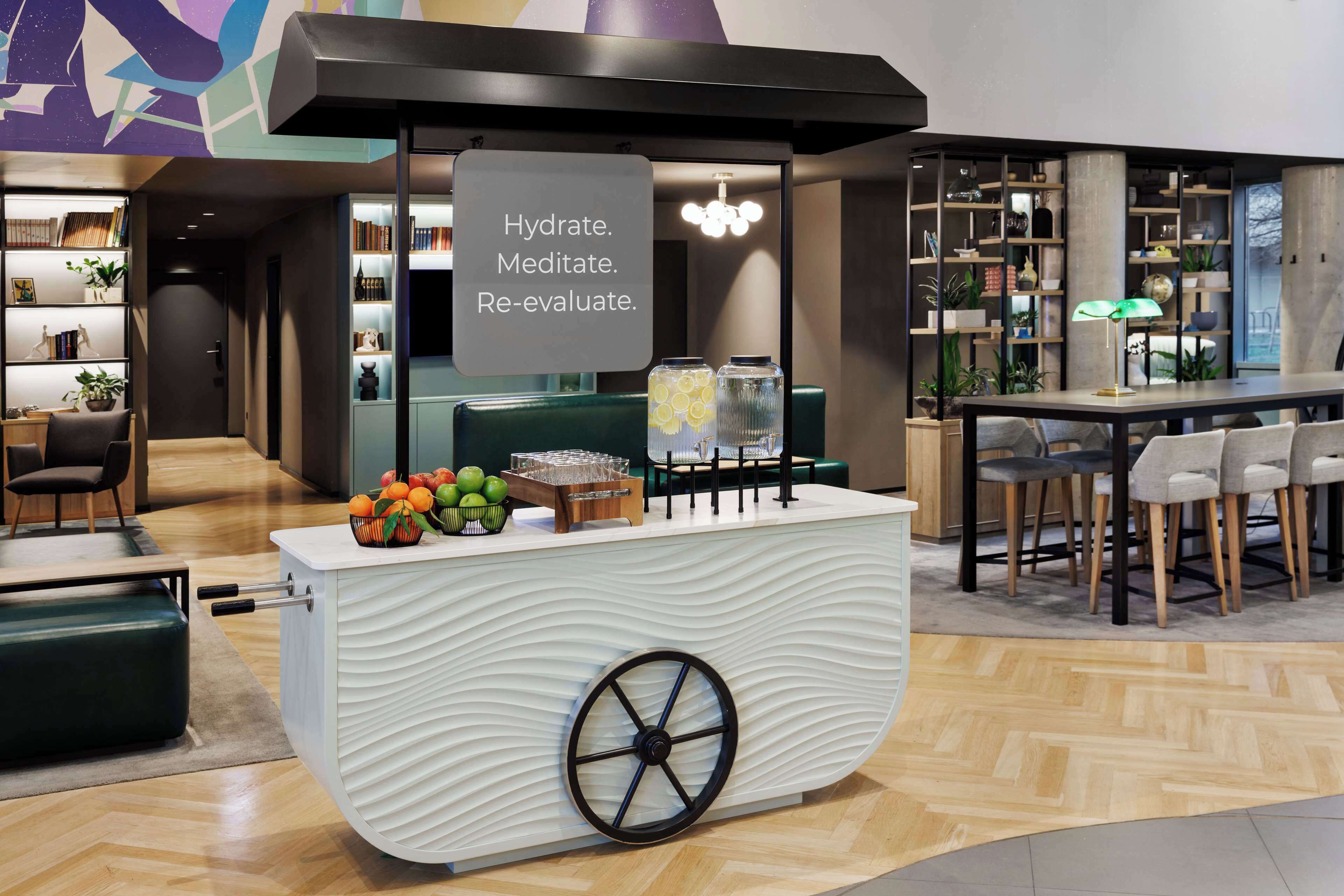 Un área de bar moderna con estación de hidratación, asientos y una estantería.