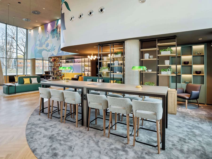 A modern kitchen with a central island, bar stools, and a seating area with a sofa and chairs.