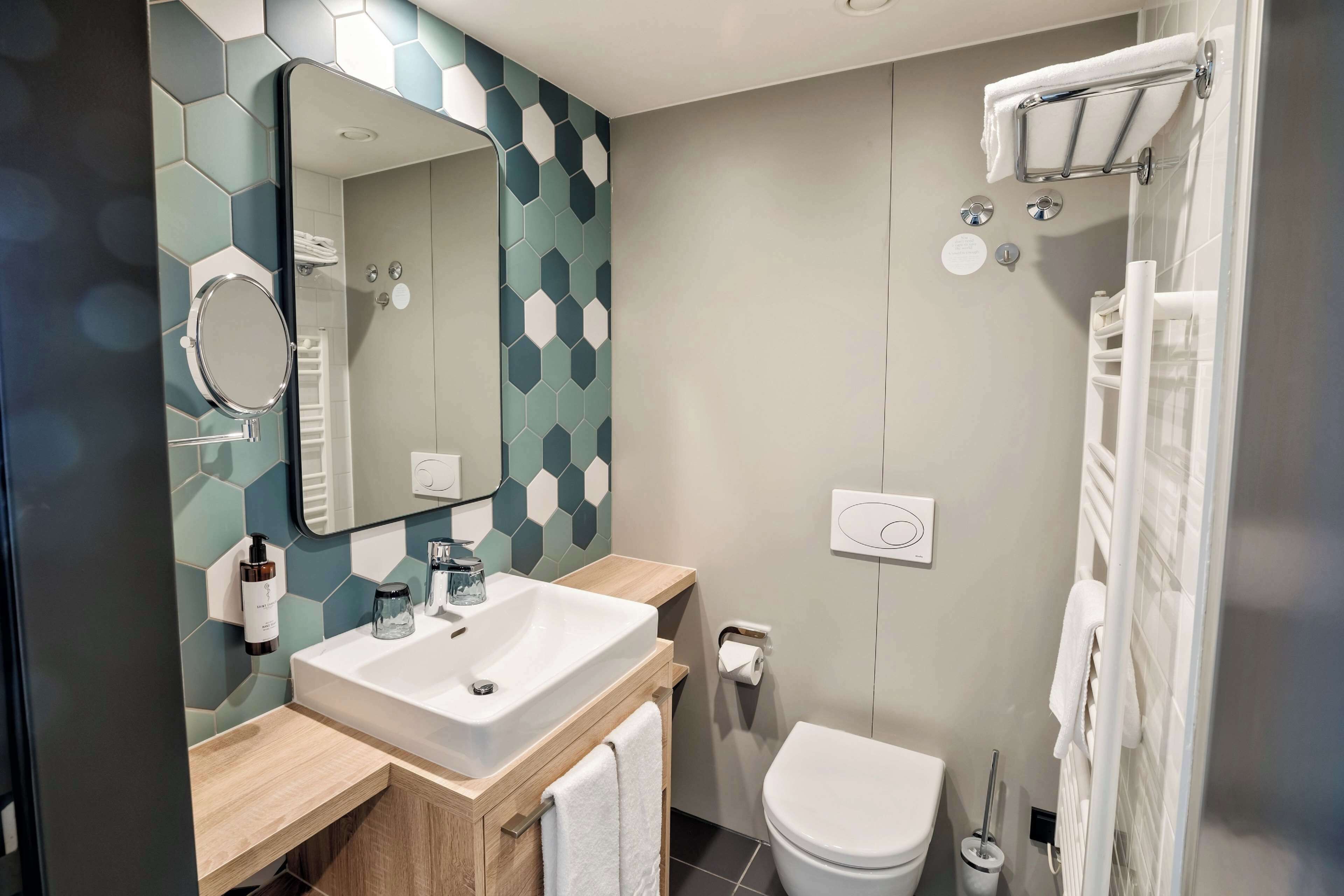 Un baño moderno con lavamanos, espejo, inodoro y ducha.
