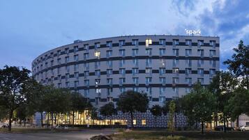 Um hotel moderno com fachada curva, várias janelas e uma placa com a inscrição "spark by Hilton".