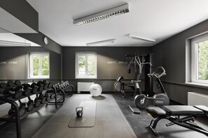 A gym with exercise equipment, dumbbells, a kettlebell, and a yoga mat. - Spark by Hilton Vienna Messe Prater (Vienna)