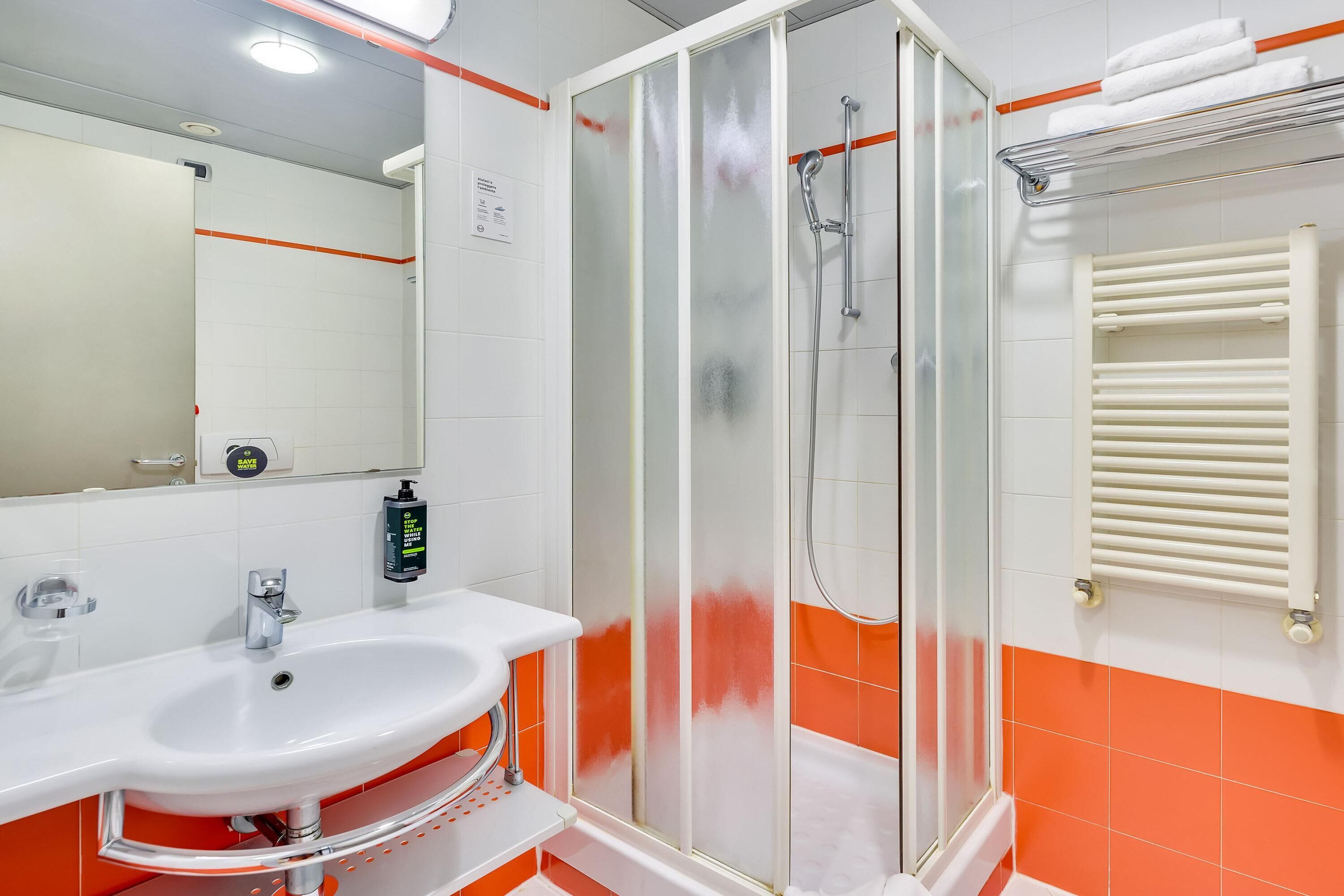 A bathroom with a white sink, a glass shower enclosure, and a towel rack.