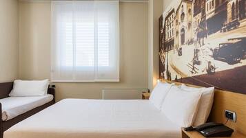 Ein Hotelzimmer mit zwei Einzelbetten, einem großen Fenster mit leichtem Vorhang, einem wandmontierten Telefon und einem Vintage-Stadtbild.