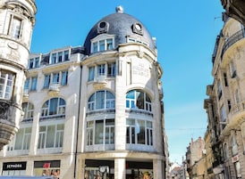 Un edificio histórico con una cúpula y ventanas de arco, que cuenta con una tienda Sephora en la planta baja.