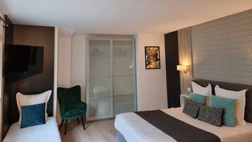A hotel room with two beds, a green chair, a sliding glass door, and a patterned wall.