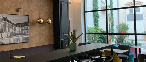 Uma área de bar moderna com um balcão comprido, banquetas e uma grande janela com vista para o exterior.