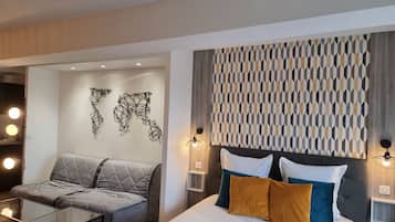 Ein modernes Hotelzimmer mit einem Bett, einer Couch und einem Glastisch.