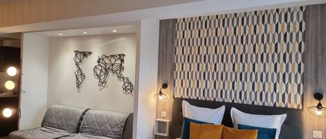 A modern hotel room with a bed, a sofa, and a glass table.