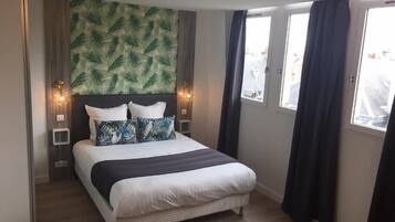 Un dormitorio con cama, pared decorada con motivos de hojas y ventana con cortinas.