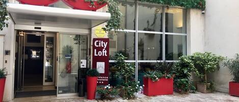 A hotel entrance with a sign reading "City Loft" and a red awning.
