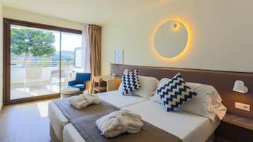 A hotel room with a large bed, two pillows, a round mirror, and a view of the outdoors.