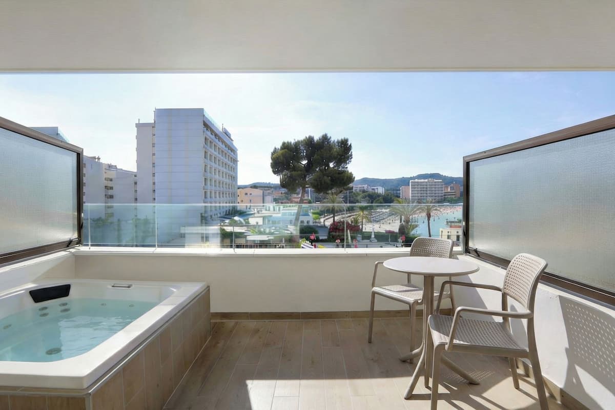 A balcony with a hot tub, a round table, and two chairs.