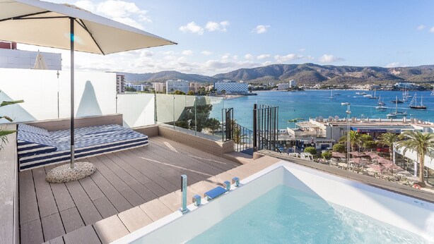 Terraza en la azotea con piscina, zona de descanso y vistas al puerto deportivo y a las montañas.