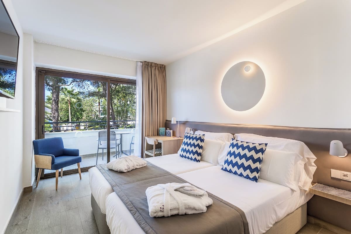 A modern hotel room with a large bed, a desk, and a chair.