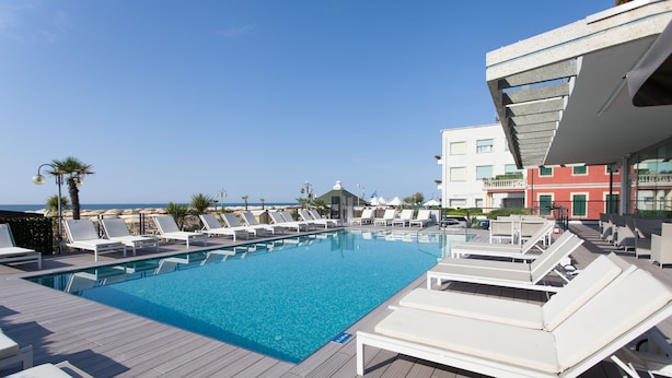 Un espace aménagé au bord de la piscine, avec des chaises longues et une vue dégagée sur la mer.