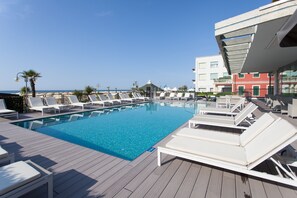 A poolside area with lounge chairs and a clear view of the sea. - Hotel Adlon (Jesolo)