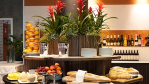 Un buffet de petit-déjeuner avec des fruits, du pain et des bouteilles de vin.