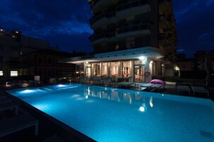 Una piscina al aire libre, sombrillas, sillones reclinables de piscina