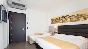 Une chambre d’hôtel avec deux lits, un grand tableau au mur, une télévision et un appareil de climatisation.