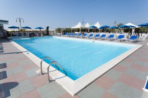 Una piscina al aire libre, sillones reclinables de piscina