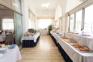 A buffet setup with multiple tables, each with plates and food items. - Hotel Marina (Jesolo)