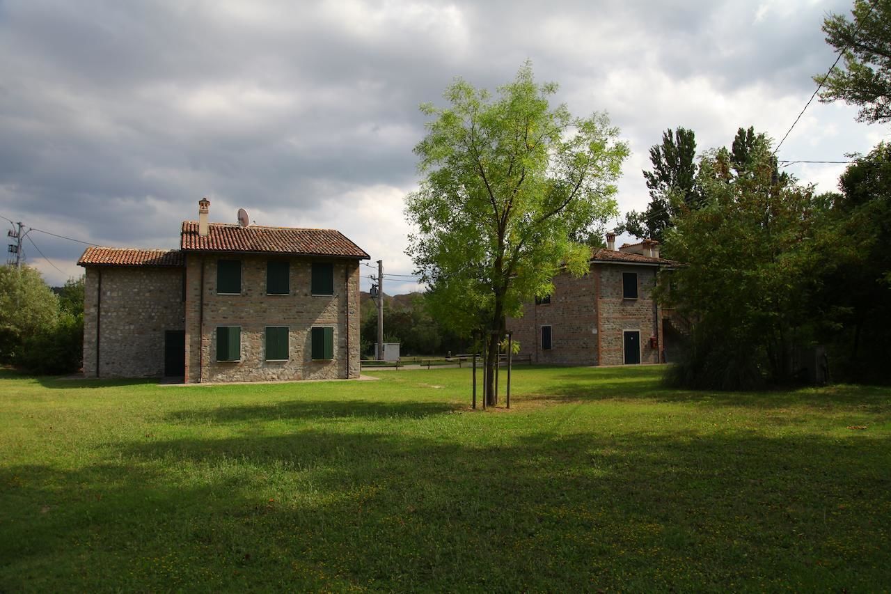 A stone building with a tiled roof, surrounded by a grassy area and trees.