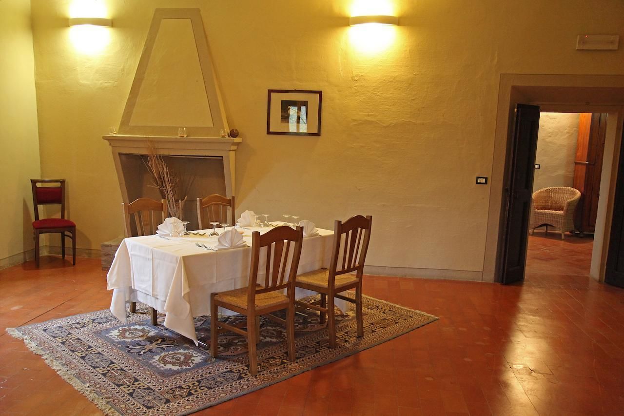 Une salle à manger avec une table dressée pour quatre personnes, une cheminée et deux appliques murales.