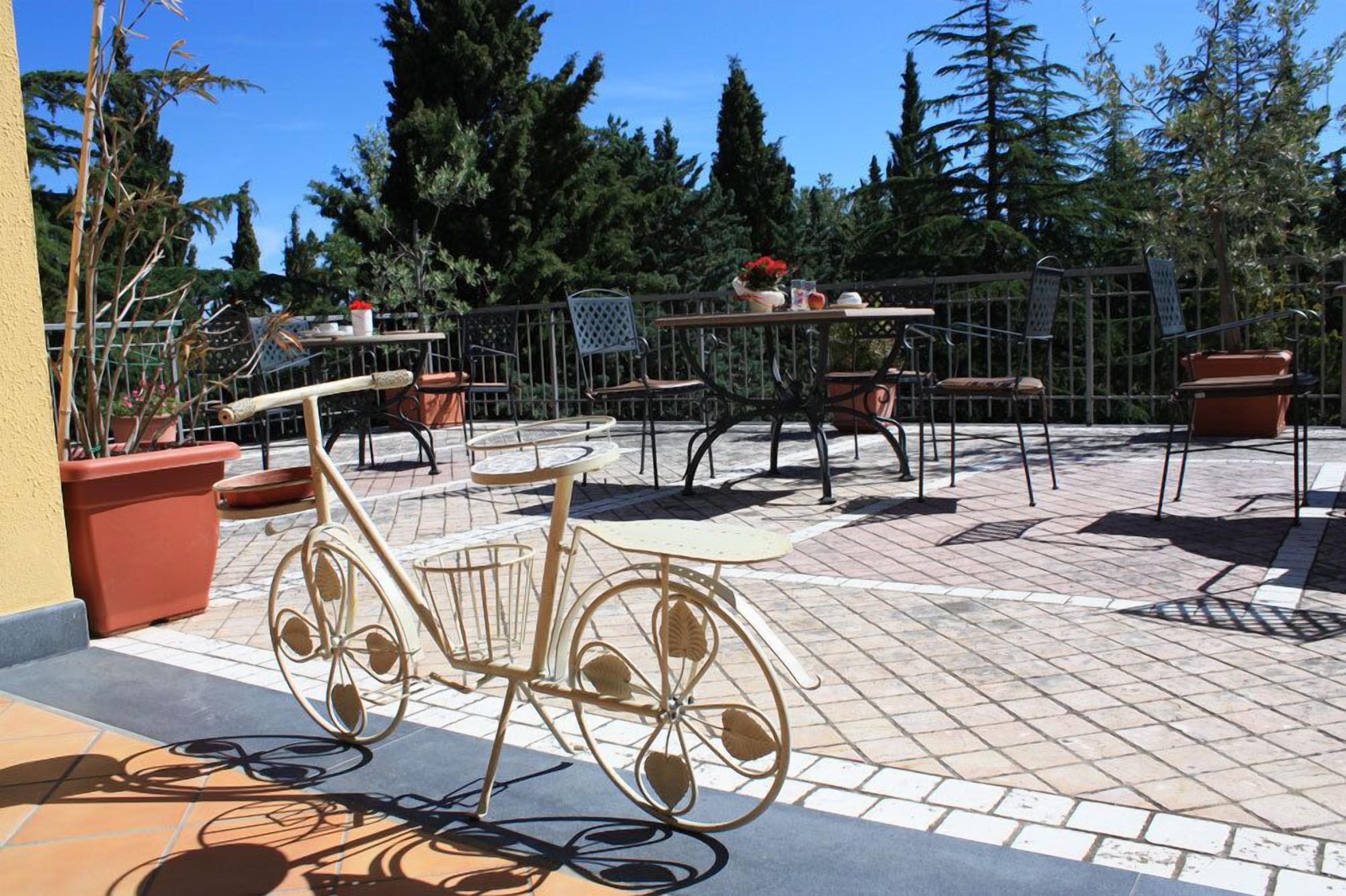 Eine Außenpatio-Terrasse mit einem Fahrrad, Tischen, Stühlen und Topfpflanzen.