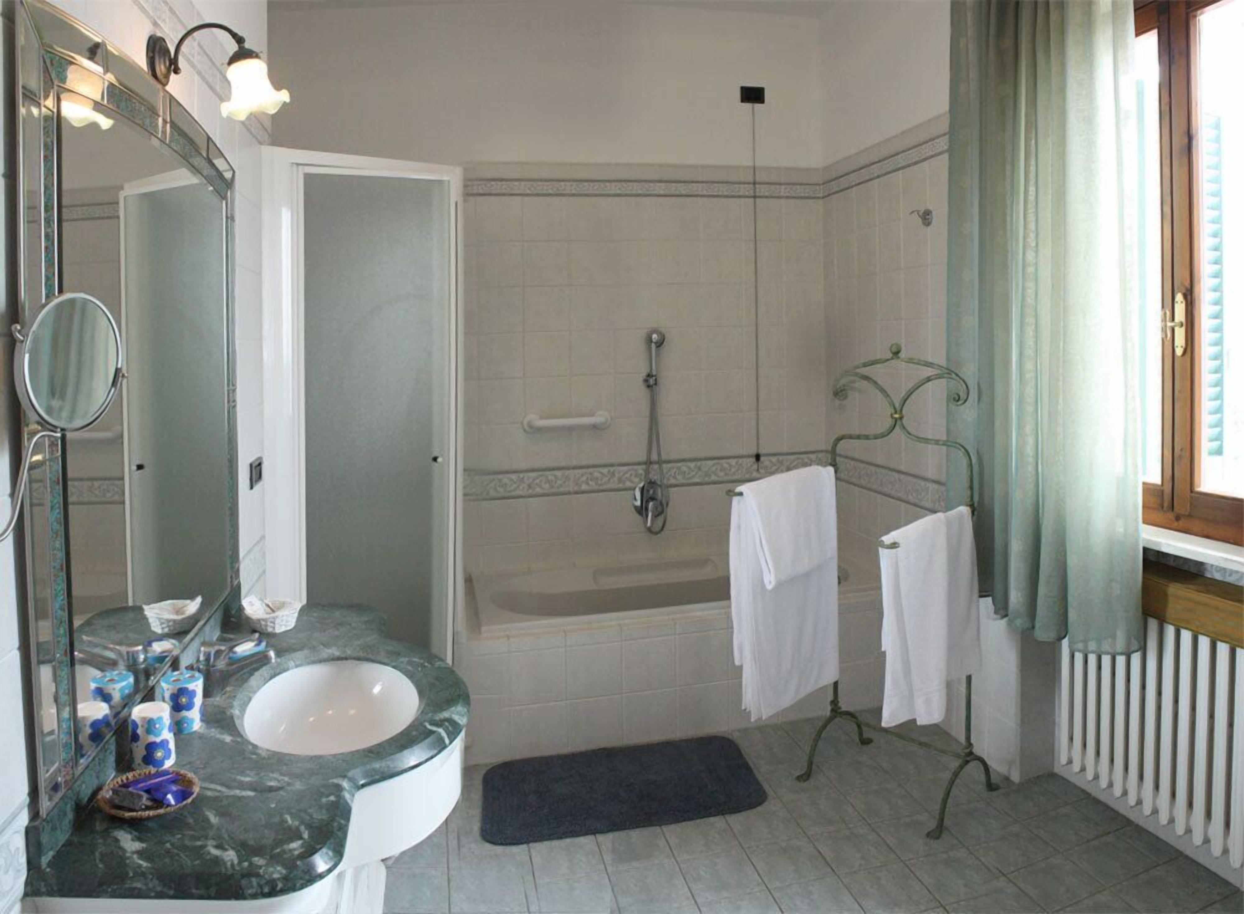 A bathroom with a sink, mirror, shower, and towel rack.