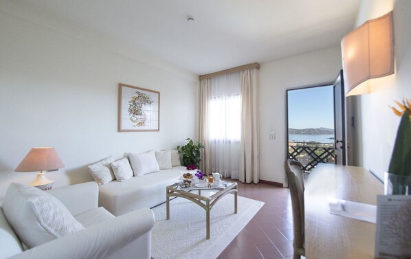 A modern living room with a sofa, coffee table, and a view of the sea. - Hotel Palau (Palau)