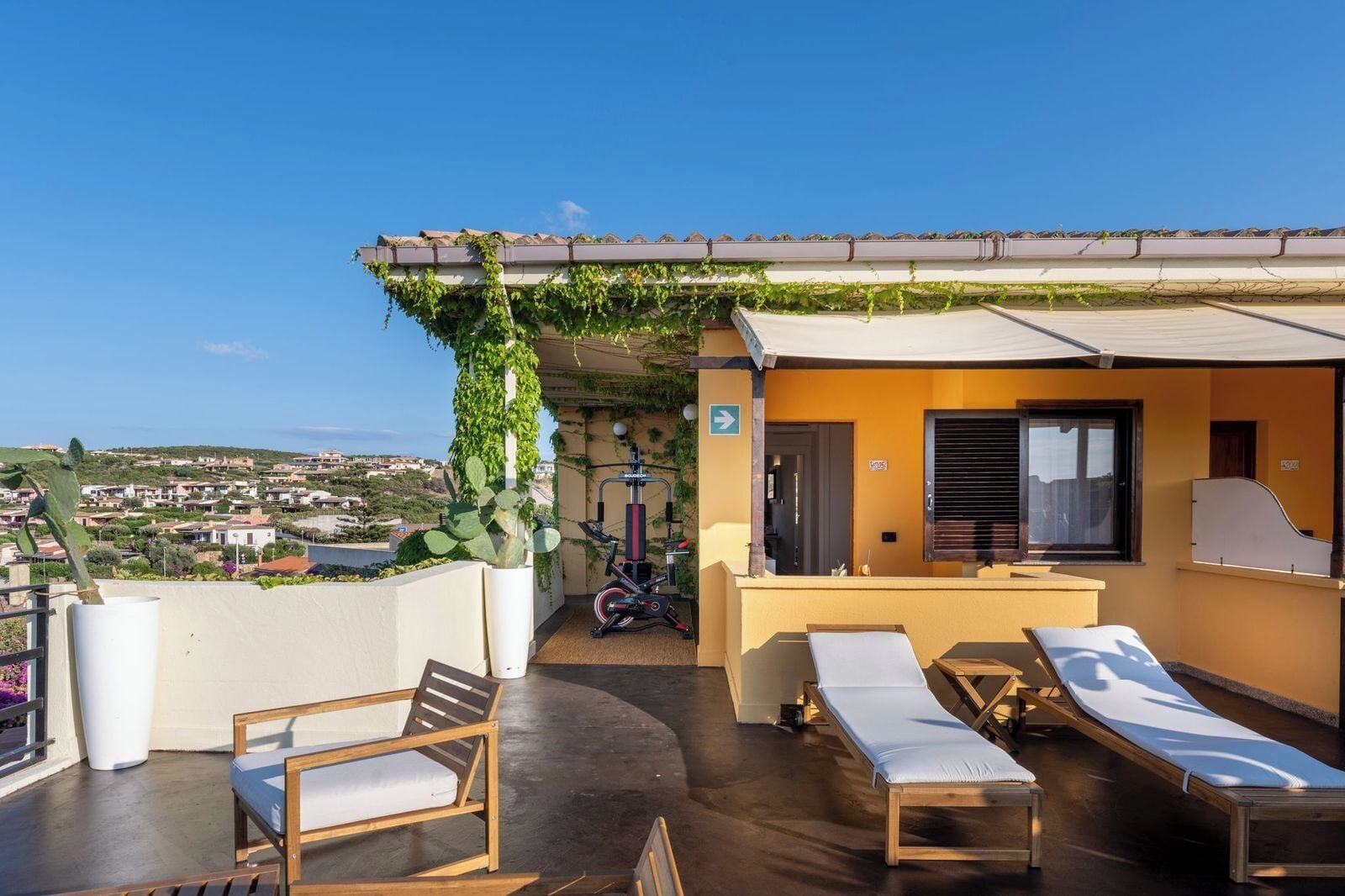 A rooftop terrace with a view of the city, a gym, and seating areas.