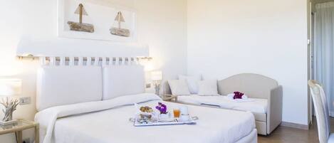 Habitación de hotel con dos camas, una mesita con productos de desayuno y un adorno en la pared sobre las camas.