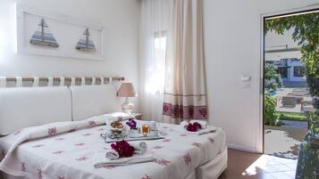 A hotel room with a bed, a table with breakfast items, a lamp, and a view of the outside.