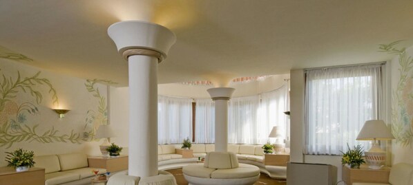 A spacious living room with a large central column, a sofa set, and a coffee table. - Hotel Palau (Palau)