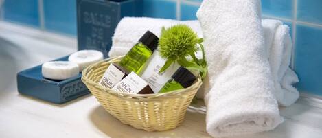 A bathroom with a blue tiled wall, a white towel, a wicker basket with toiletries, and a soap dish.