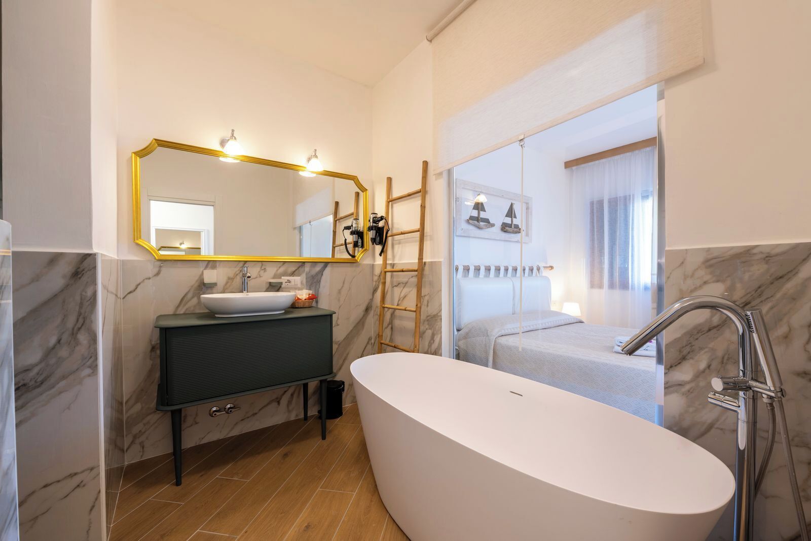 A modern bathroom with a freestanding bathtub, a vanity with a marble countertop, and a large mirror with lights.