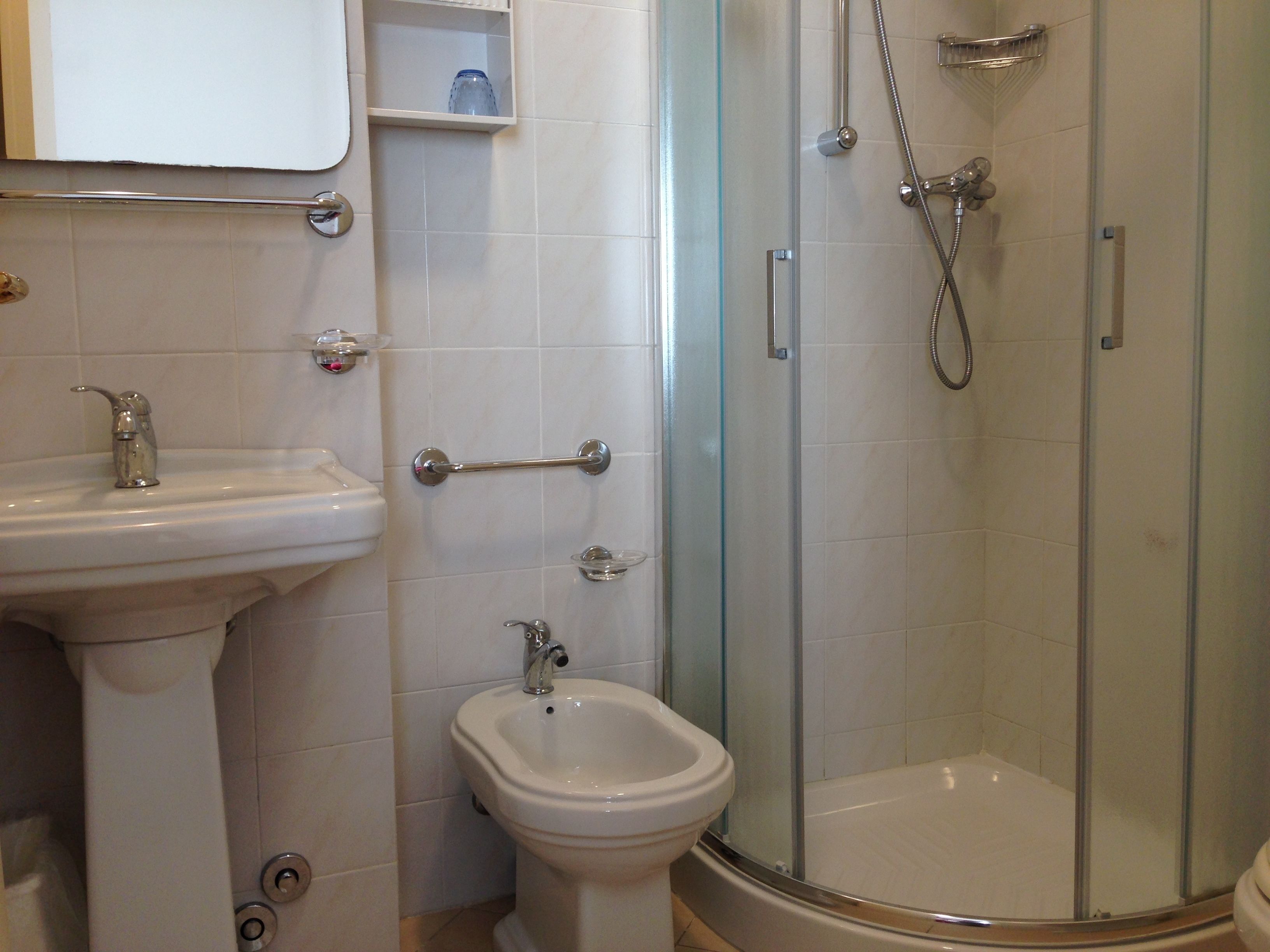A bathroom with a sink, bidet, and glass-enclosed shower.