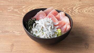 Un tazón de sashimi con algas y wasabi sobre una mesa de madera.