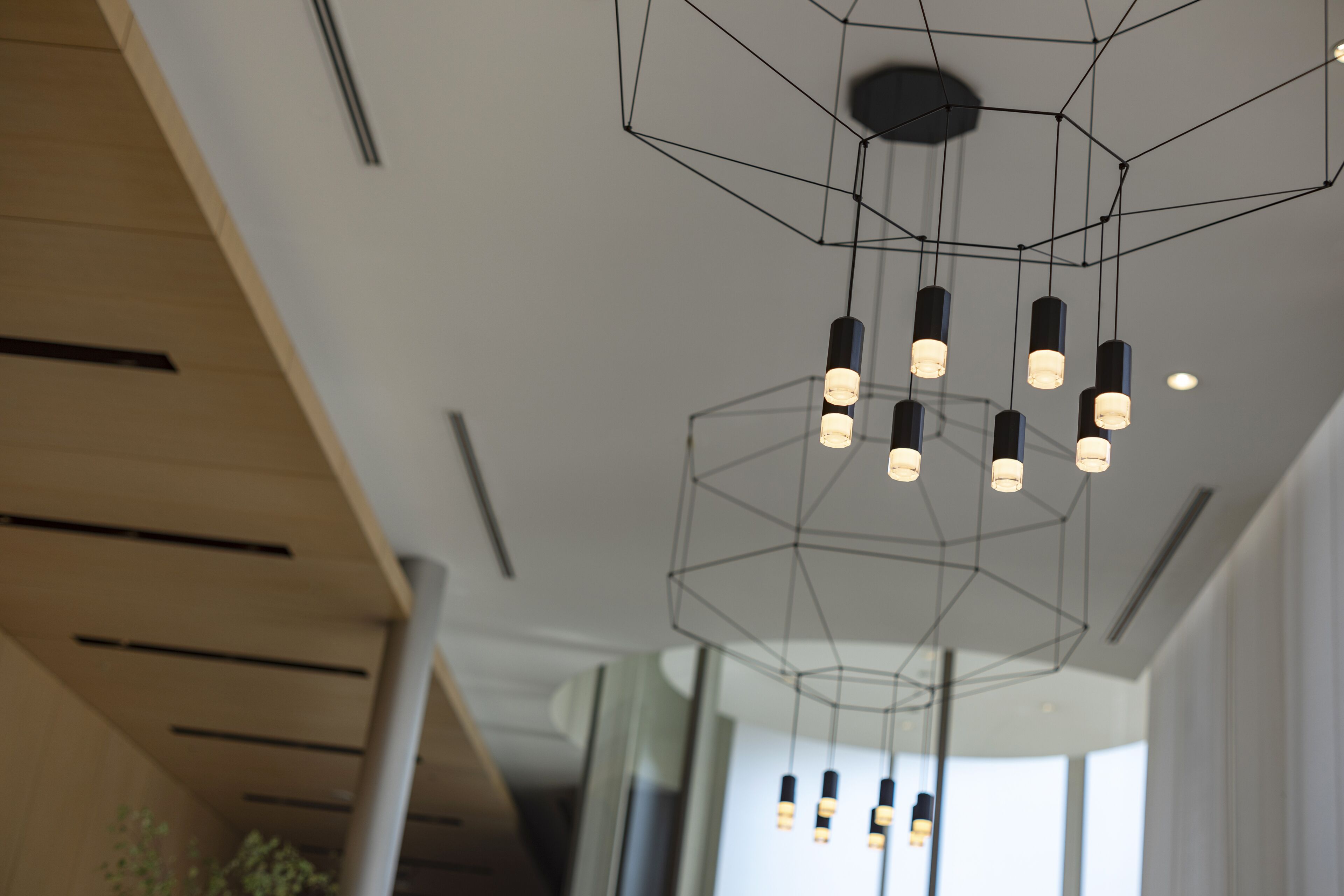 A modern interior with a geometric ceiling light fixture and a wooden ceiling structure.