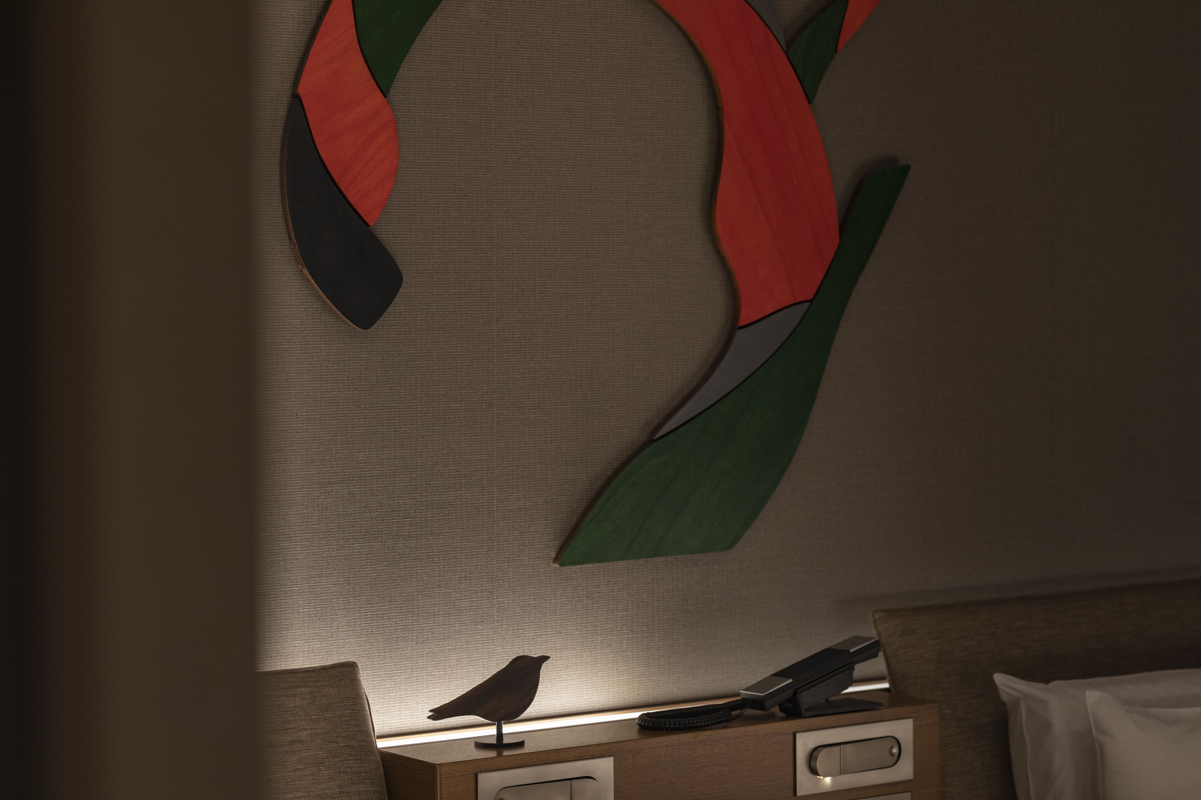 Una habitación con una cama, una mesita de noche con lámpara y una obra de arte abstracto colgada en la pared.