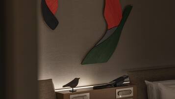 Una habitación con una cama, una mesita de noche con lámpara y una obra de arte abstracto colgada en la pared.
