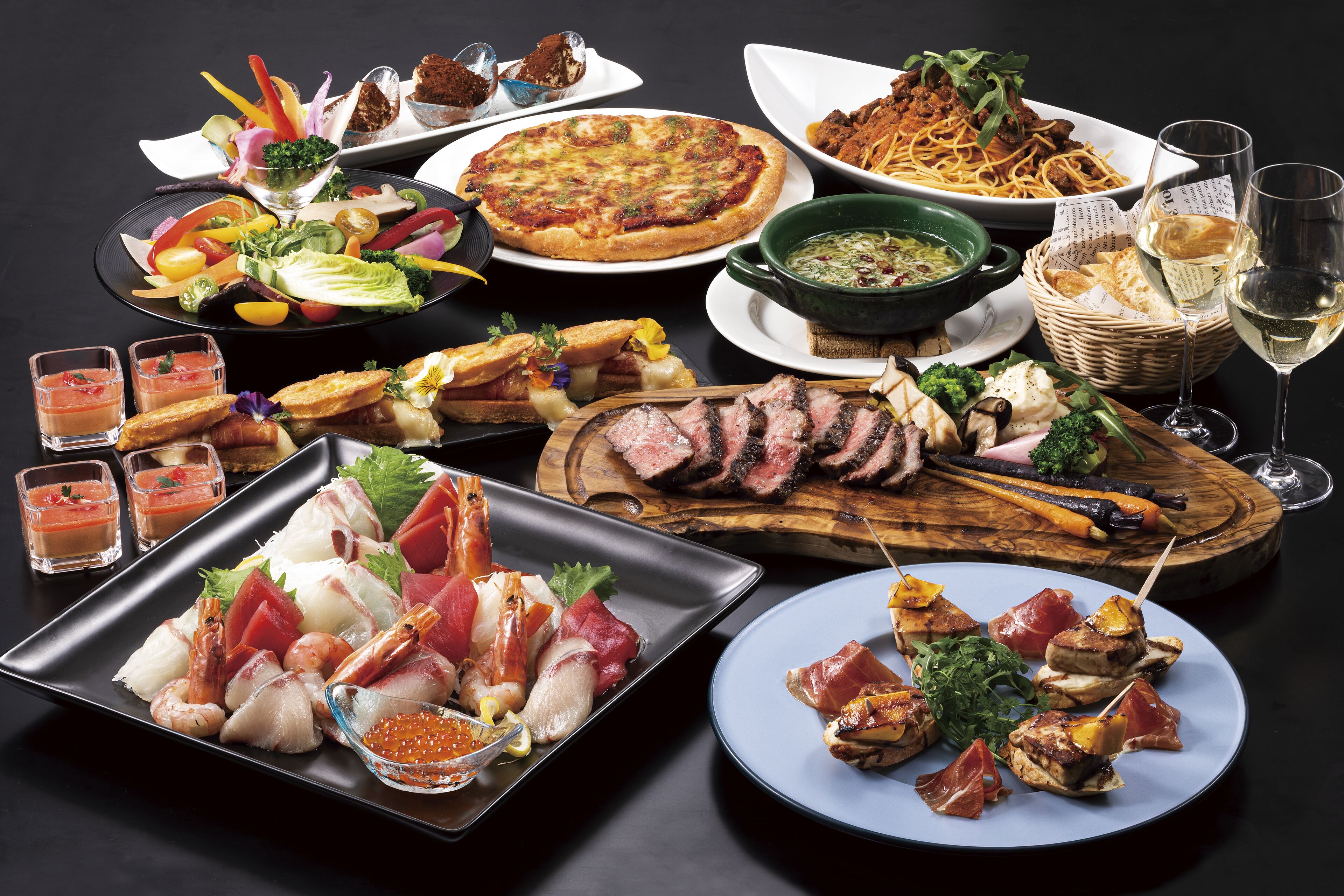 A variety of dishes including pizza, seafood, and meat, arranged on a table.