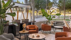 Un espace de détente moderne, doté de sièges, d’un comptoir d’accueil et de grandes fenêtres donnant sur la rue.