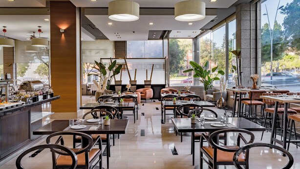 Un restaurant moderne doté d’un bar central, de nombreuses tables et de chaises.