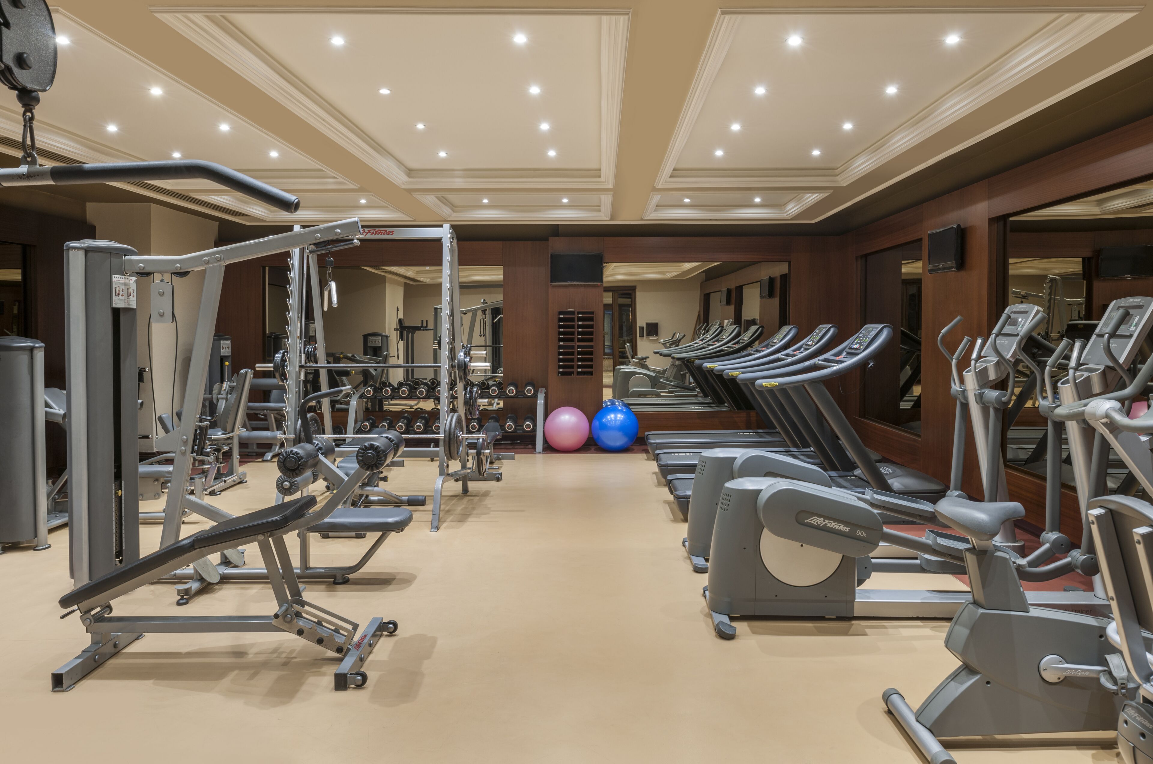 Une salle de sport équipée de divers appareils d’exercice, notamment des tapis de course, des appareils elliptiques et des machines de musculation.