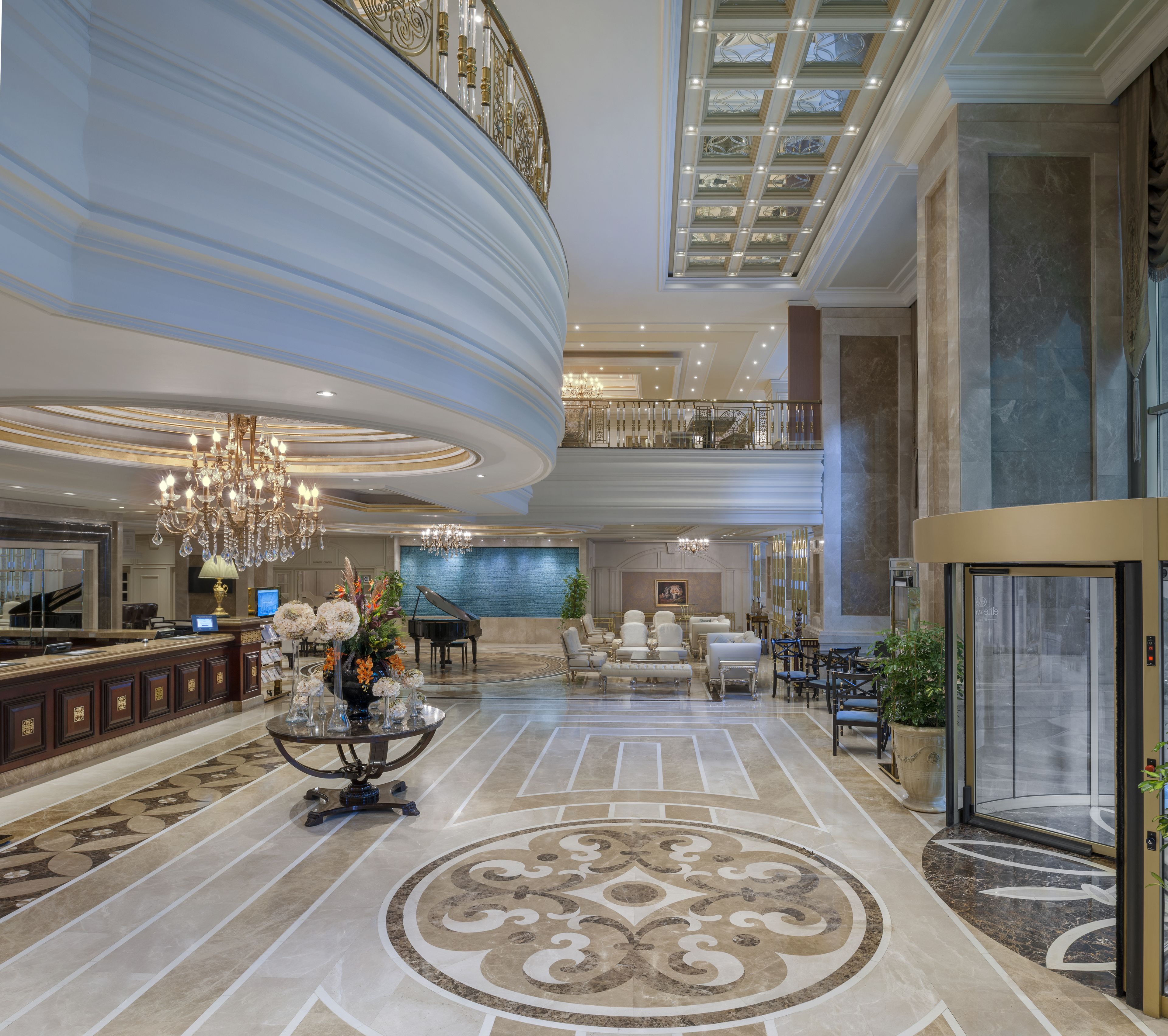 Un vestíbulo imponente con un piano, candelabros y una alfombra decorativa grande.