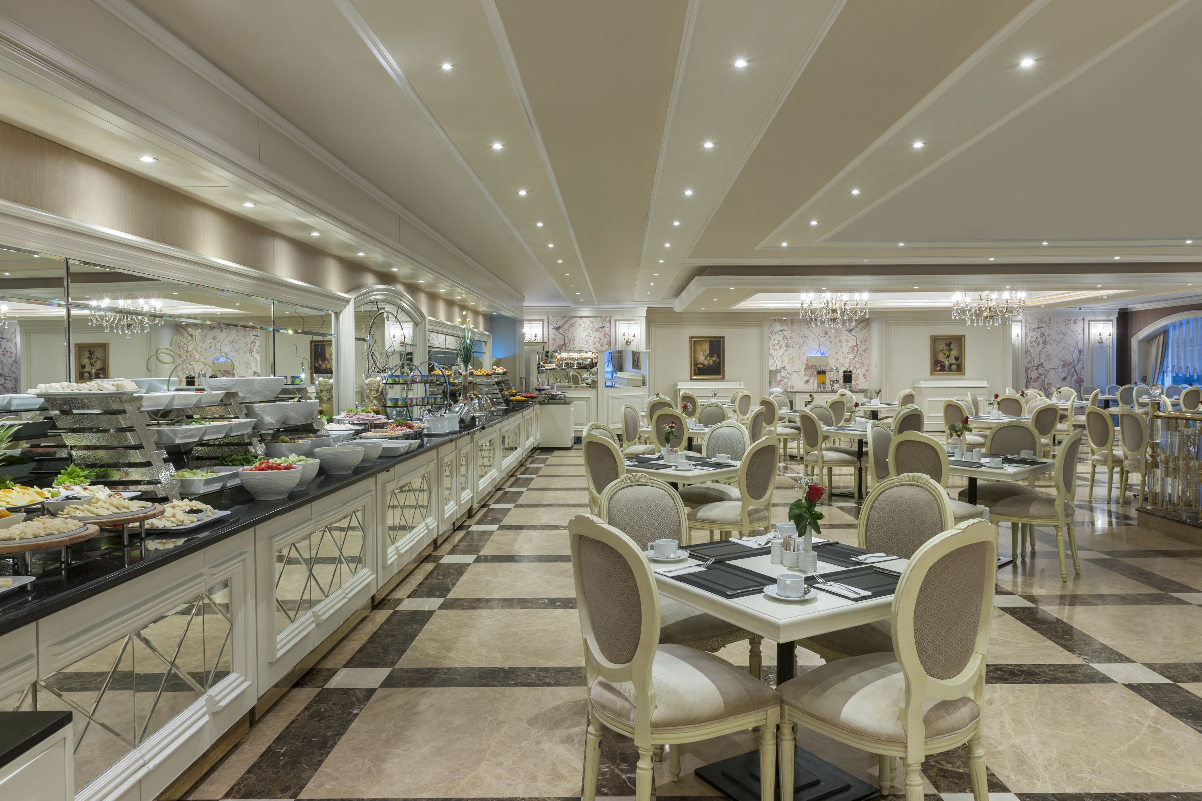 A spacious dining area with multiple tables and chairs, a buffet with various food items, and a checkered floor pattern.