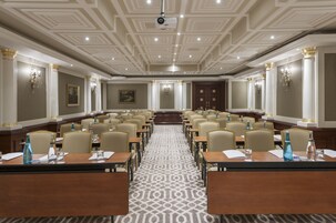 Una sala conferenze con un lungo tavolo, sedie e un tappeto decorato.