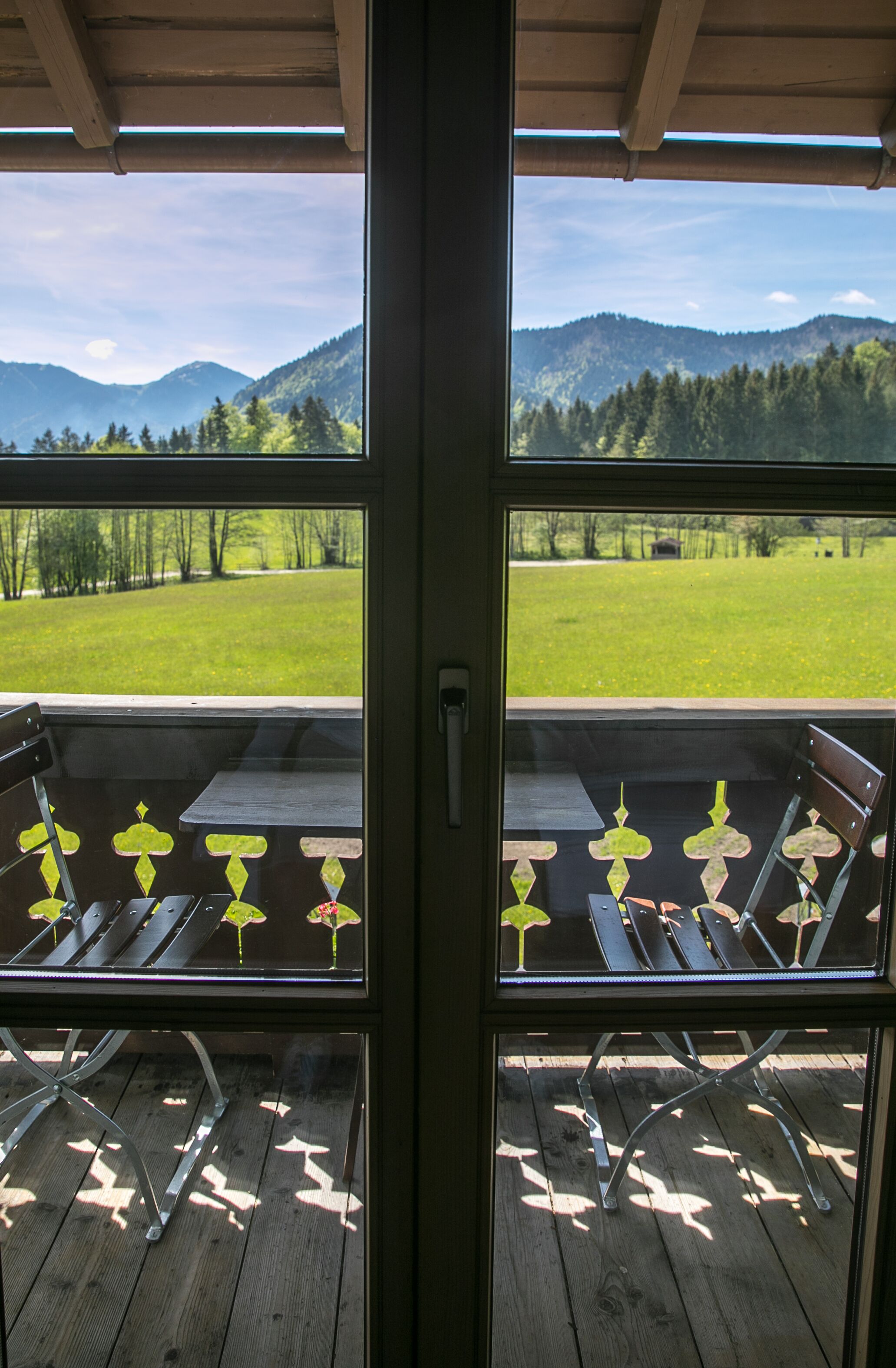 Blick von einem Balkon mit Holzboden, Metallstühlen und einem Tisch.